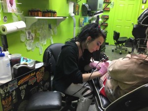 Weaver pursuing her dream and tattooing a client. 