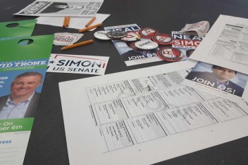 A table at the town hall meeting filled with literature, buttons, and sample ballots.