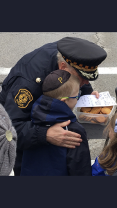 Officer hugging a young boy who appears to have given him cookies and a note